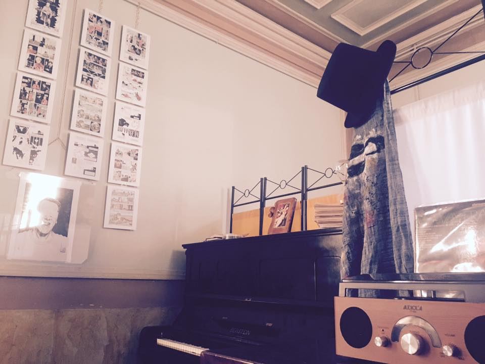 Il pianoforte con le tavole di un fumetto esposte alla parete